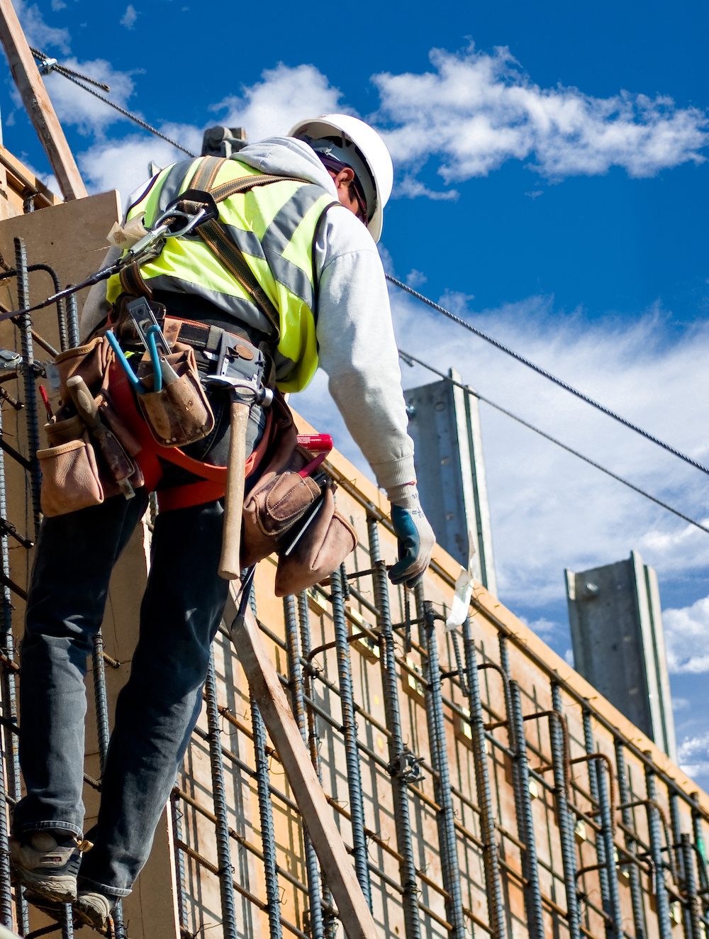 A construction worker on a high wall against a cloudy sky.