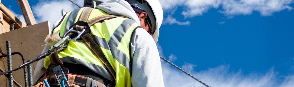 A construction worker on a high wall against a cloudy sky.